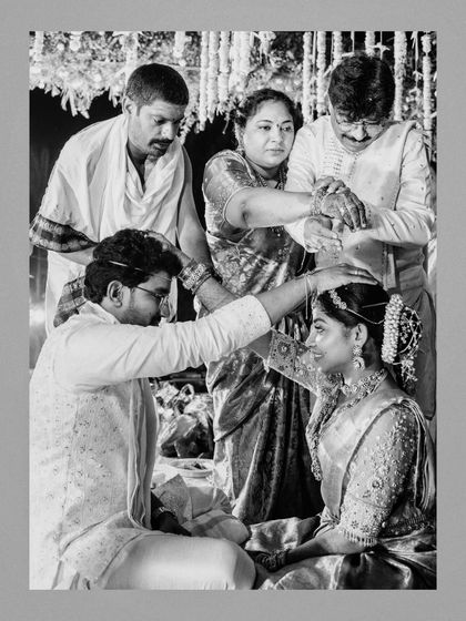 A timeless black and white photo of Uhanjali and Abhi receiving blessings from their parents during their South Indian wedding ceremony.