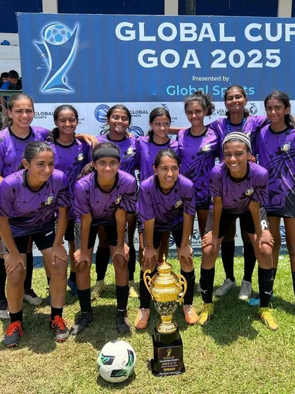 The U17 team posing for a formal photo with the Global Cup trophy in front of the tournament banner in Goa.