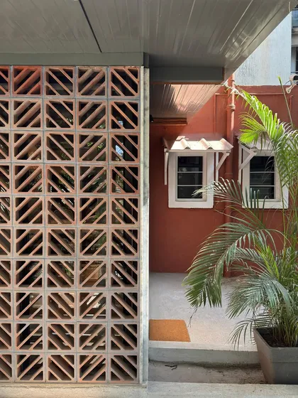 A detail shot of the terracotta jali facade, contrasting with the original red-painted wall of the main building. This shows how we designed the extension to complement the character of the existing heritage structure.