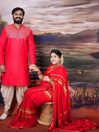 A formal portrait of an expecting couple in traditional red attire. The composition is classic and elegant, perfect for a timeless family keepsake.