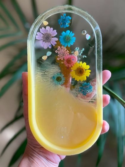 A beautiful resin tray with pressed flowers, showcasing a different color palette and design. Each artist creates a truly unique piece.