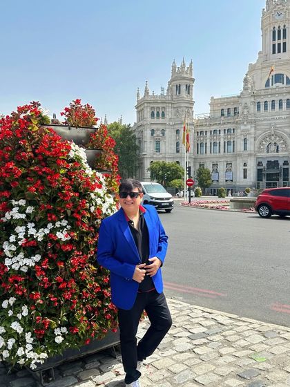 Posing next to a vibrant floral arrangement in Madrid, adding another layer of color to the scene.