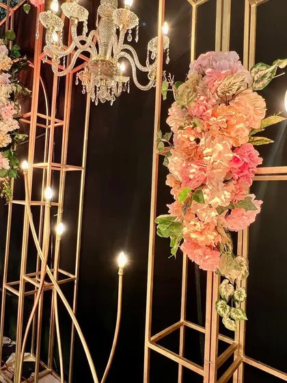 Another detail shot of the stage backdrop, showing the combination of the gold-painted metal frame, chandeliers, and pastel floral decor.