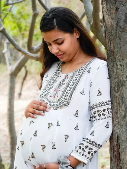 A tender moment captured during an outdoor maternity shoot. The focus is on the mother's connection with her baby.