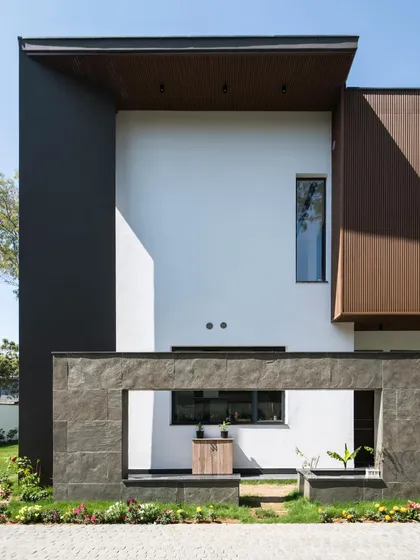 The south facade of Triveni Farmhouse. I designed it as a compact version of the main front facade, using the same projecting volumes and contrasting materials like wood and stone to create a strong first impression.