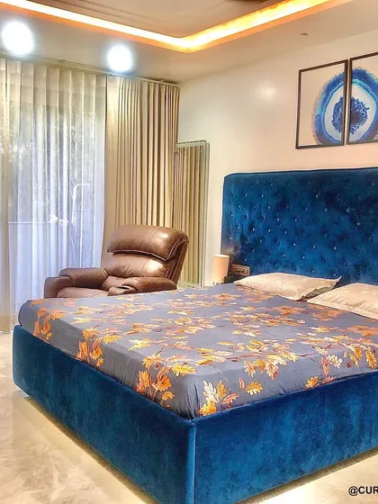 I love how this royal blue bedroom turned out. The deep blue velvet bed creates a rich focal point, complemented by a leather recliner and artwork that adds a pop of color.