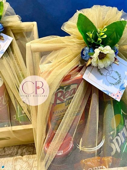 These confectionery hampers were designed as engagement favours. Each pinewood basket is packed with a variety of drinks and snacks, and elegantly wrapped in beige tulle with a floral accent.