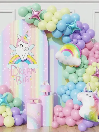 A "Dream Big" unicorn-themed party with a pastel rainbow arch backdrop. The setup is adorned with a soft-colored balloon garland and unicorn props, creating an inspiring and magical atmosphere.