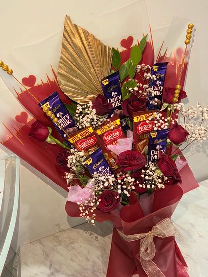 Another angle of the popular chocolate and rose bouquet. The combination of red wrapping, fresh flowers, and familiar candy bars makes it a perfect gift for Valentine's Day or a birthday.