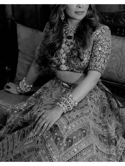 A detailed black and white shot of the bride's Sabyasachi lehenga and jewelry. This portrait highlights the exquisite craftsmanship and her elegant posture.