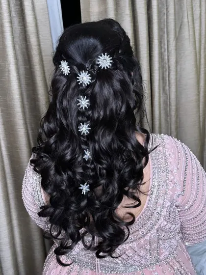 Love is in the hair. This glamorous open hairstyle is perfect for a reception or sangeet, featuring soft waves and sparkling star-shaped accessories.