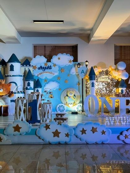 A whimsical castle theme for a first birthday, featuring a 3D castle, fluffy cloud props, and a teddy bear prince.