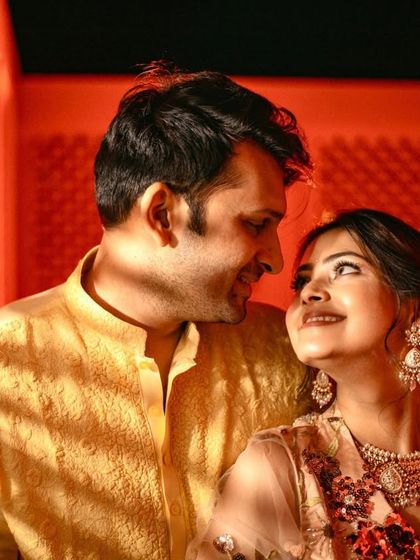 A warm, intimate portrait of the couple under dramatic red lighting, capturing the mood of the evening.