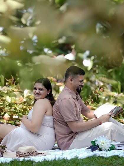 A sweet pose with the couple sitting back-to-back, enjoying a quiet moment together in the park.
