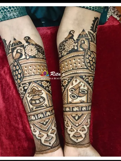 A detailed shot of the arm work, showcasing majestic peacocks, a kalash for prosperity, and a dhol to represent wedding celebrations.