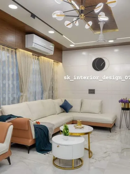 A contemporary living room with a two-tone L-shaped sofa and nested coffee tables. The wood-paneled ceiling detail and modern chandelier elevate the overall design.