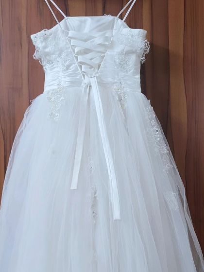 A full view of the back of the white corset gown. The lace-up back and full tulle skirt create a classic and romantic bridal or pre-wedding look.