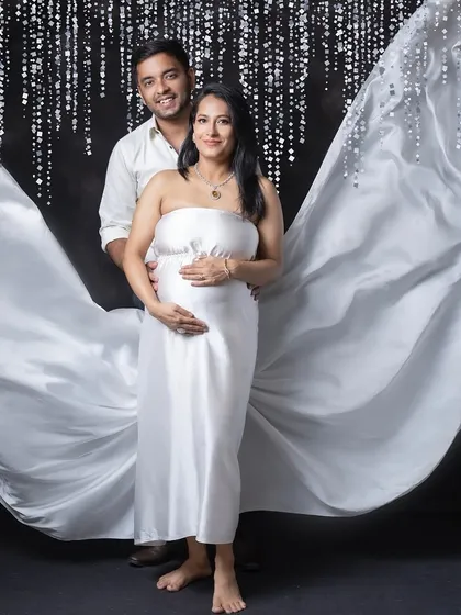A full-length portrait of the couple against a sparkling backdrop. The flowing white fabric creates a sense of movement and grace, framing them in a beautiful, ethereal way.