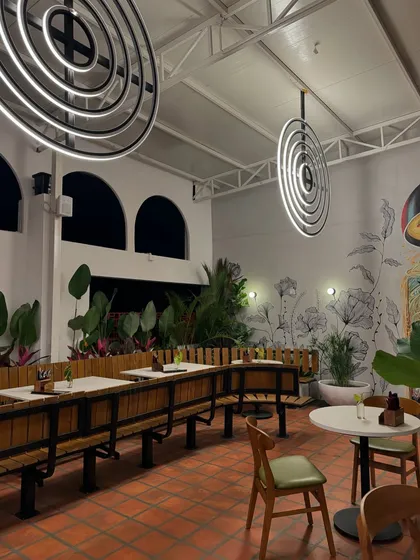 The interior of a rooftop cafe we recently landscaped. The combination of large potted plants, wall murals, and modern furniture creates a curated and elevated ambiance that is both stylish and serene.