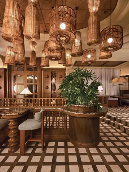 A detail of the seating, where a cluster of rattan chandeliers creates a warm, inviting canopy. The turned-wood details of the railings and furniture add a layer of traditional craftsmanship.
