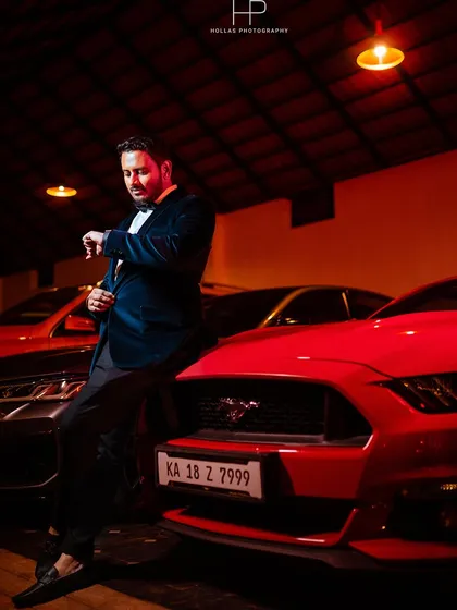 A solo portrait of the groom looking sharp at the cocktail celebration. The moody lighting and luxury cars in the background create a sophisticated and powerful image.