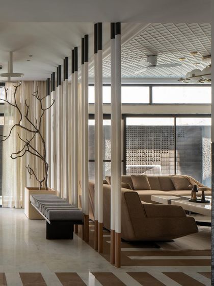 Upon entering, the ambiance transitions from rugged to refined. This foyer features a plush bench and a striking mirror installation that enhances the play of light and shadow, creating a grand and welcoming experience.