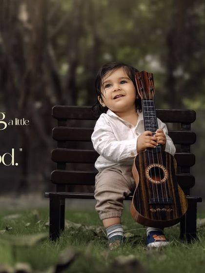 Sprinkling a little magic into childhood. A toddler holds a ukulele while sitting on a park bench.