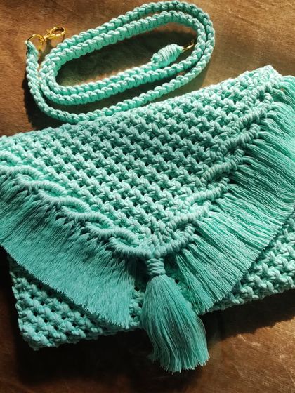 This fringed macrame clutch in a refreshing seafoam green is a perfect mix of our craftsmanship and a modern aesthetic. It's a highly functional piece that doesn't compromise on style.