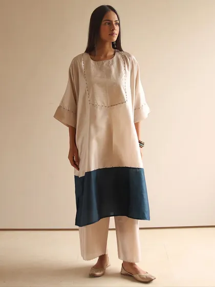 When comfort meets sophistication. This model wears a simple color-blocked tunic in beige and navy, paired with matching pants for an effortlessly chic look.