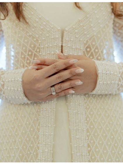 A close-up of the bride's hands, showing her elegant manicure and beautiful wedding ring. A simple yet significant detail of her wedding day.