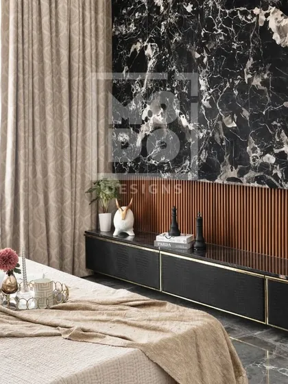 In this bedroom, a dramatic black marble feature wall serves as a backdrop for the TV unit. The contrast between the dark marble and the warm, soft bedding creates a sense of balanced luxury.