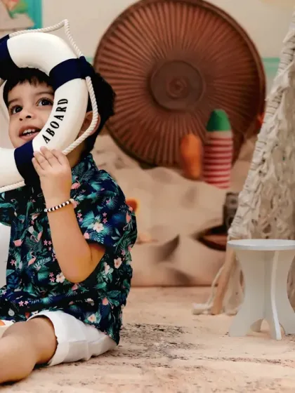This little boy is having a great time at the beach, playing with a lifebuoy prop during his second birthday shoot.