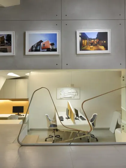 The open design of my studio, with the lower-level workstations visible through a glass railing. The wall above features framed photographs of our completed projects, serving as a source of inspiration for the team.