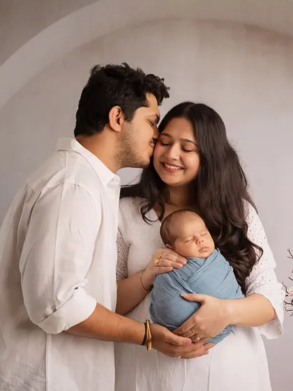 A father's gentle kiss for the mother of his child, as she holds their sleeping newborn. This is a story of love and new beginnings, captured with a soft, romantic feel.