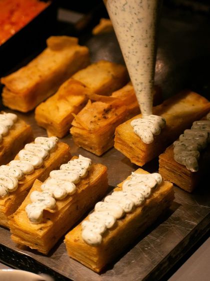A close-up of potato terrines being piped with a dill cream for an event.
