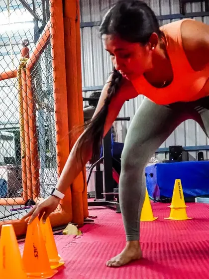 A female member performs an agility drill with cones. This exercise is crucial for improving footwork, speed, and the ability to change direction quickly, which is essential in any combat sport.