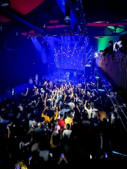 Showtime at White Lotus Club. A high-angle view shows a full house, with everyone's hands in the air, ready for a night of Bollywood and commercial hits.