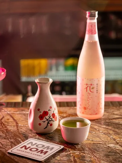 A sake bottle and cup, highlighting an international offering. The styling is clean and respects the cultural origin of the beverage.