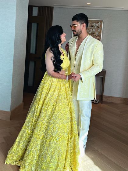 A bride in a white gown for her cocktail party, her hair styled in soft, elegant waves with a side part.