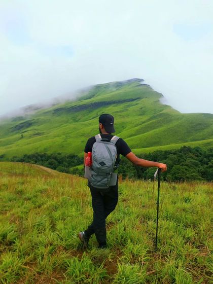 I will go to the secret gardens in my mind. A trekker stands before the misty, cloud-covered peaks of the Western Ghats.