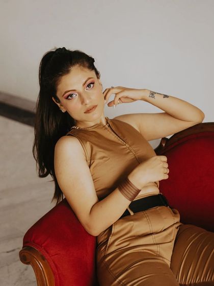 A closer shot from the vintage red chair session. The focus on the subject's expression and the warm tones create an inviting and stylish indoor portrait.