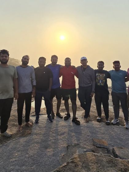 A group of friends with their arms around each other, enjoying the sunrise together.