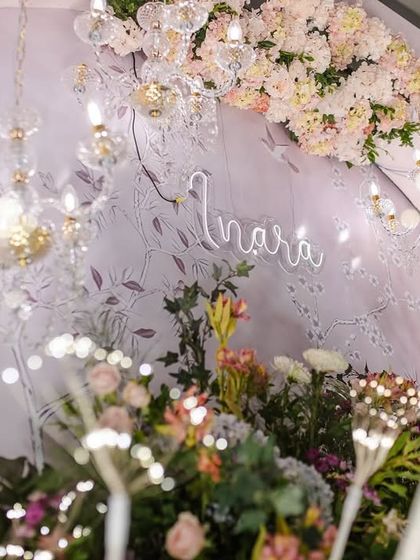 An artistic shot of the naming ceremony decor, with the "Inara" sign glowing amidst fairy lights and flowers. The entire setup was designed to feel magical and ethereal.