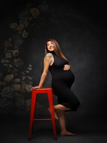 A happy and confident portrait using a bright red stool for a pop of color. The floral hoop adds a touch of elegance to this modern shot.