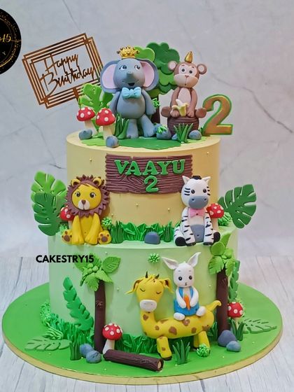 A grand 6kg two-tier animal kingdom cake for a second birthday. This chocolate cake is filled with adorable jungle animals and lush green foliage.