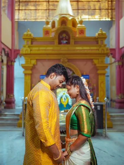 A tender moment between a South Indian couple in a temple. Their foreheads touching signifies a deep connection and receiving blessings together at the start of their journey.