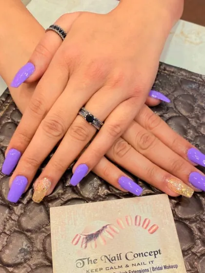 A bold set of long, square nails in a vibrant lavender color. The ring fingers are accented with a gold glitter ombre effect for a touch of warmth and sparkle.