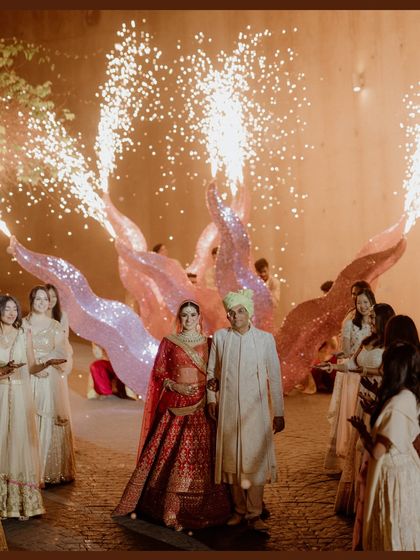 The bride's grand entrance, flanked by performers with sparkling props. This shot captures the drama and excitement of her arrival at the wedding ceremony.