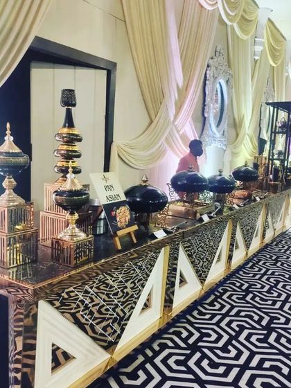A Pan-Asian food station featuring ornate black and gold serving dishes. The setup is designed to reflect the exotic nature of the cuisine being served.
