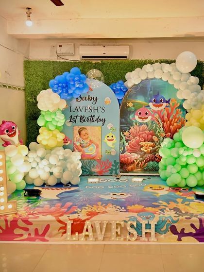 An underwater Baby Shark theme for a first birthday. This decoration includes themed backdrops, character foil balloons, and an ocean-colored floor print to complete the look.